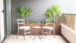 Un balcon avec deux chaises et une petite table, entouré de plantes en pot.