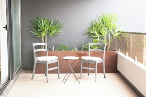 A balcony with two chairs and a small table, surrounded by potted plants. - Siena: Bright and modern 2-bedroom apartment (Santa Cruz de la Sierra)