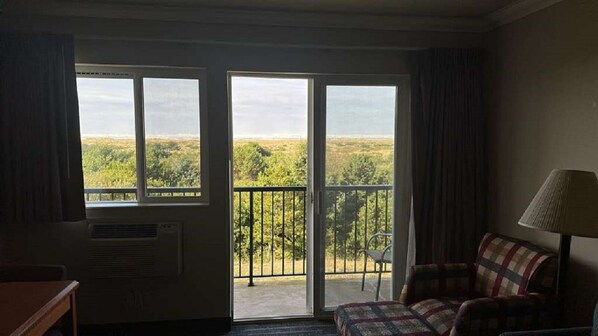Une chambre d’hôtel avec un balcon, un canapé, une table et une lampe.