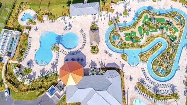 Vista aérea de un complejo turístico con varias piscinas, una piscina central grande y un elemento acuático serpenteante.