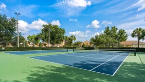A tennis court with a net, surrounded by trees and buildings. - 2627 Windsor Hills (Kissimmee)