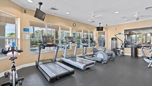A gym with treadmills, ellipticals, and weight machines, large windows, and a clock on the wall. - 2627 Windsor Hills (Kissimmee)