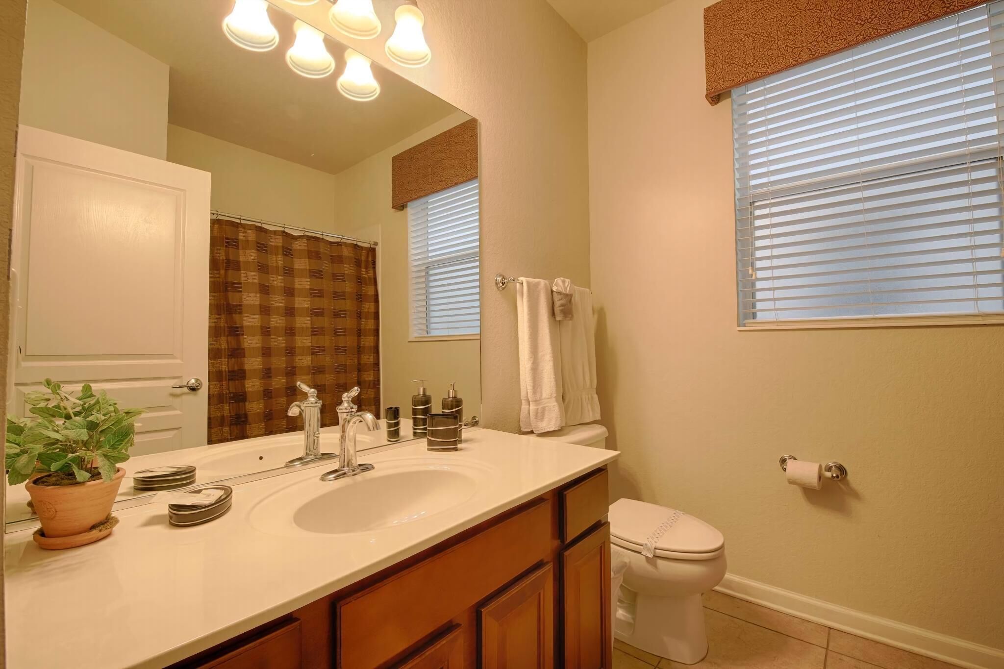 Un baño con lavamanos, espejo, toallero y retrete.