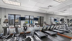 Een fitnessruimte met meerdere loopbanden, hometrainers en elliptische machines.