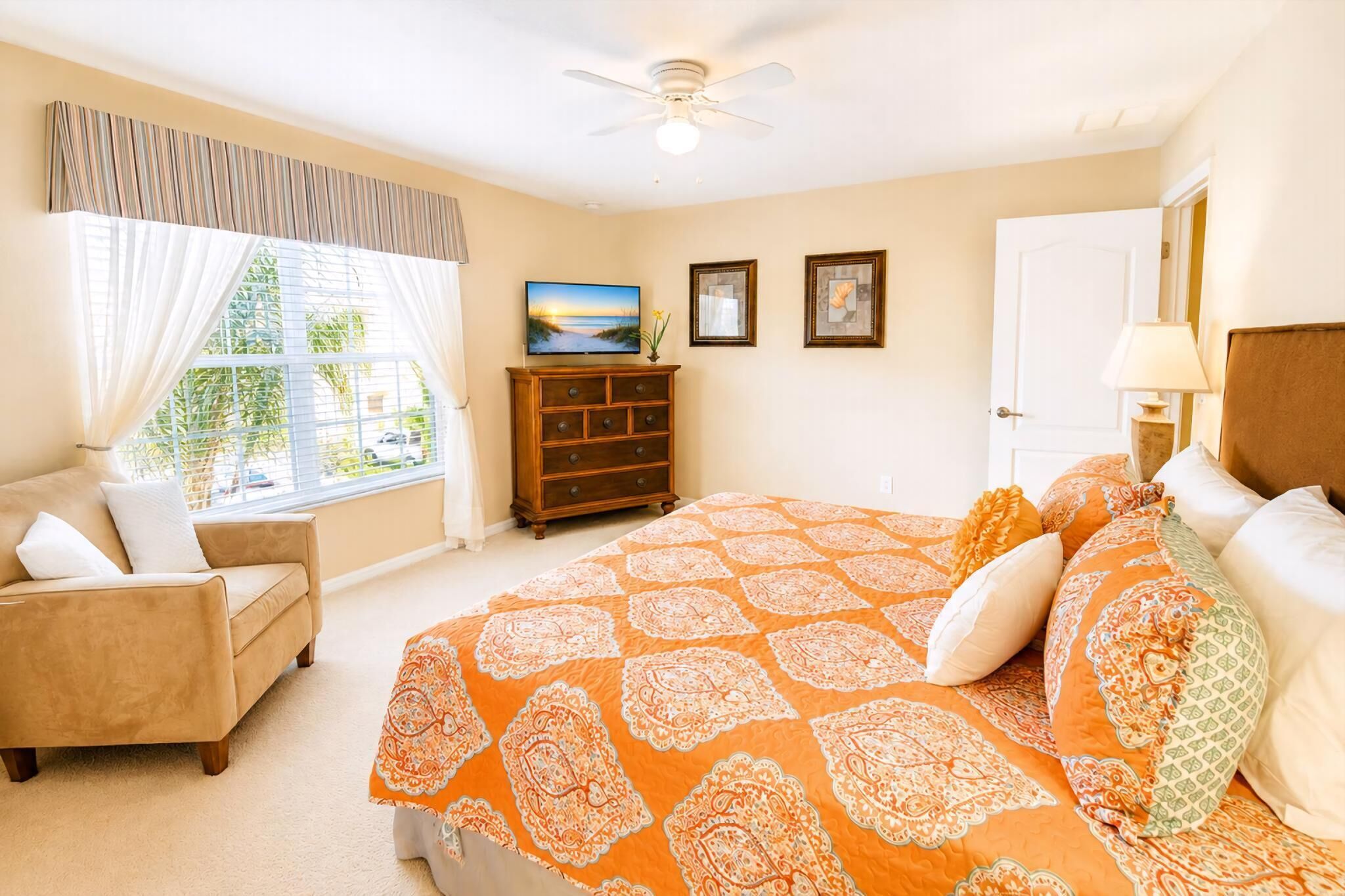 A bedroom with a bed, a sofa, a TV, and a window with curtains.