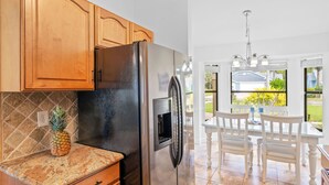 A kitchen with wooden cabinets, a stainless steel refrigerator, and a granite countertop. - Peaceful Lakeview 3BR. Heated Pool Retreat.  (Naples)