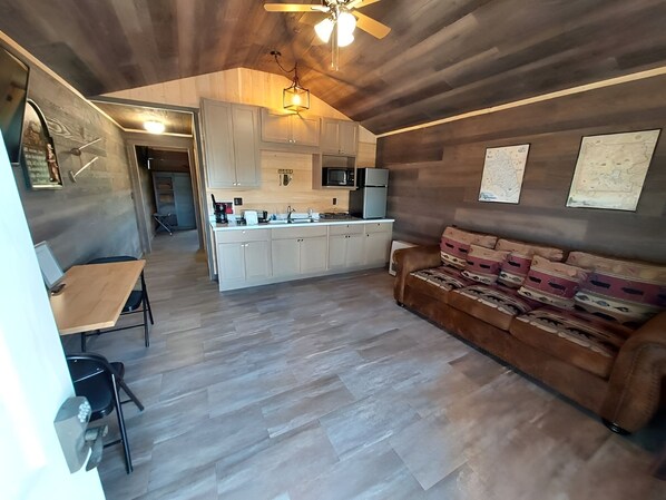 A modern kitchen with white cabinets, a central island, and a ceiling fan. - Cabin with Living Area, Kitchen, and Scenic Outdoors Ideal for Nature Seekers (Anaconda)