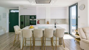 Una cocina moderna con gabinetes blancos, una isla central y un comedor con cuatro sillas.