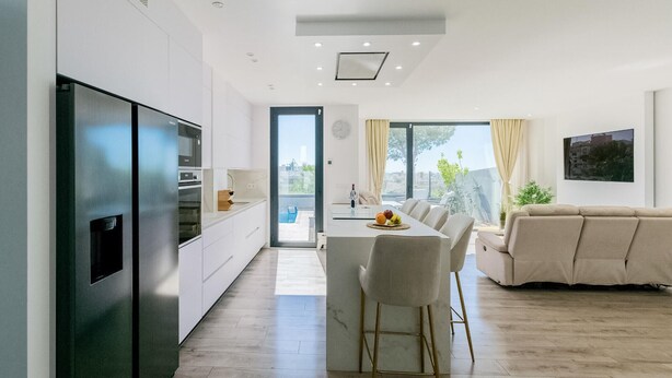 Una cocina moderna con horno empotrado, un comedor con mesa y sillas, y un sofá.