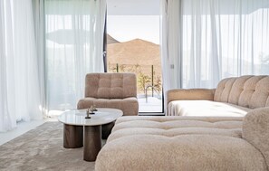 A modern living room with a sofa, armchair, and coffee table, large windows with sheer curtains, and a view of a hill. - Gorgeous home in Mijas (Mijas)