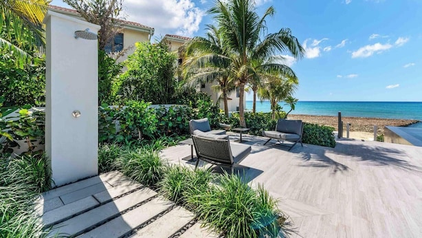 A patio with outdoor furniture, a palm tree, and a view of the beach. - Aqua 4 on Seven Mile Beach (Seven Mile Beach)
