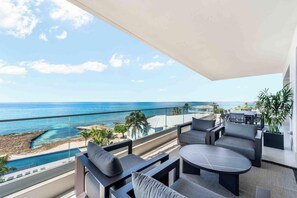 A balcony with outdoor furniture, a view of the ocean, and a swimming pool. - Aqua 4 on Seven Mile Beach (Seven Mile Beach)