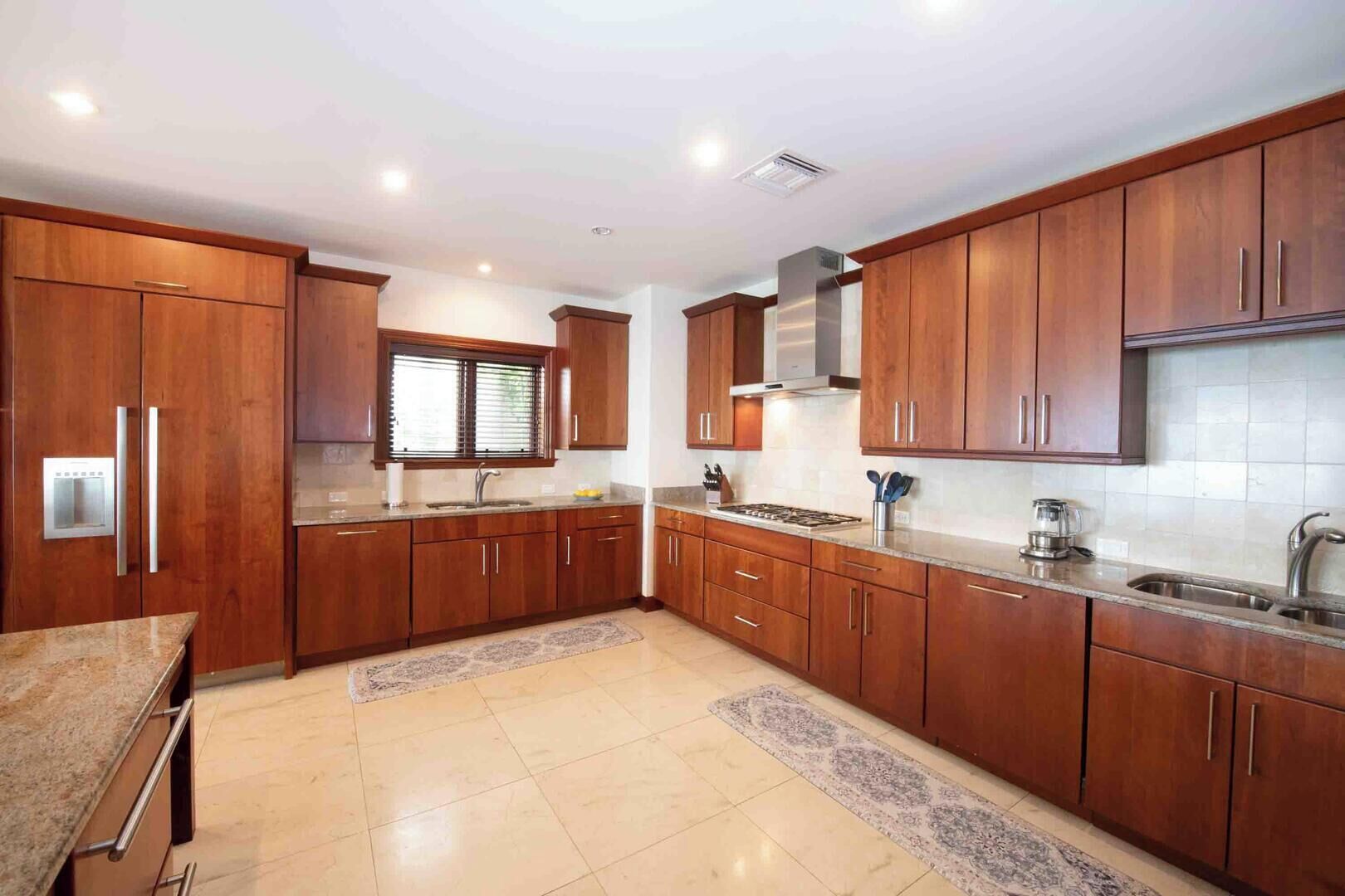 Una cocina moderna con armarios de madera, un lavamanos de acero inoxidable y una estufa empotrada.