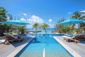 A pool with a view of the ocean, lounge chairs, and umbrellas. - Casa Luna (George Town)