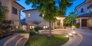 A courtyard with a central tree, curved pathways, and a building with multiple windows and doors. - Casa Luna (George Town)