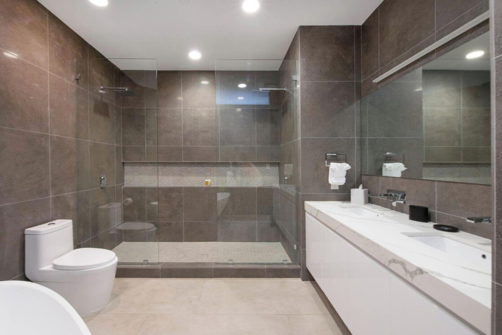 A modern bathroom with a glass-enclosed shower, a white toilet, and a large mirror.