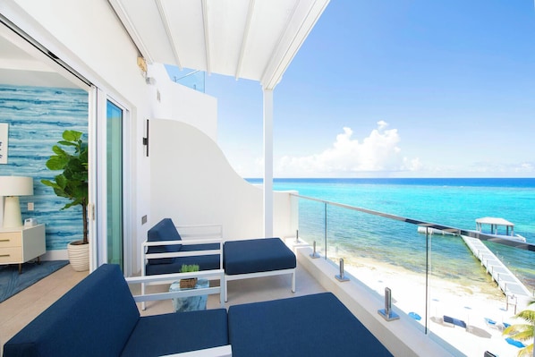A balcony with a view of the ocean, a sofa, a small table, and a plant.
