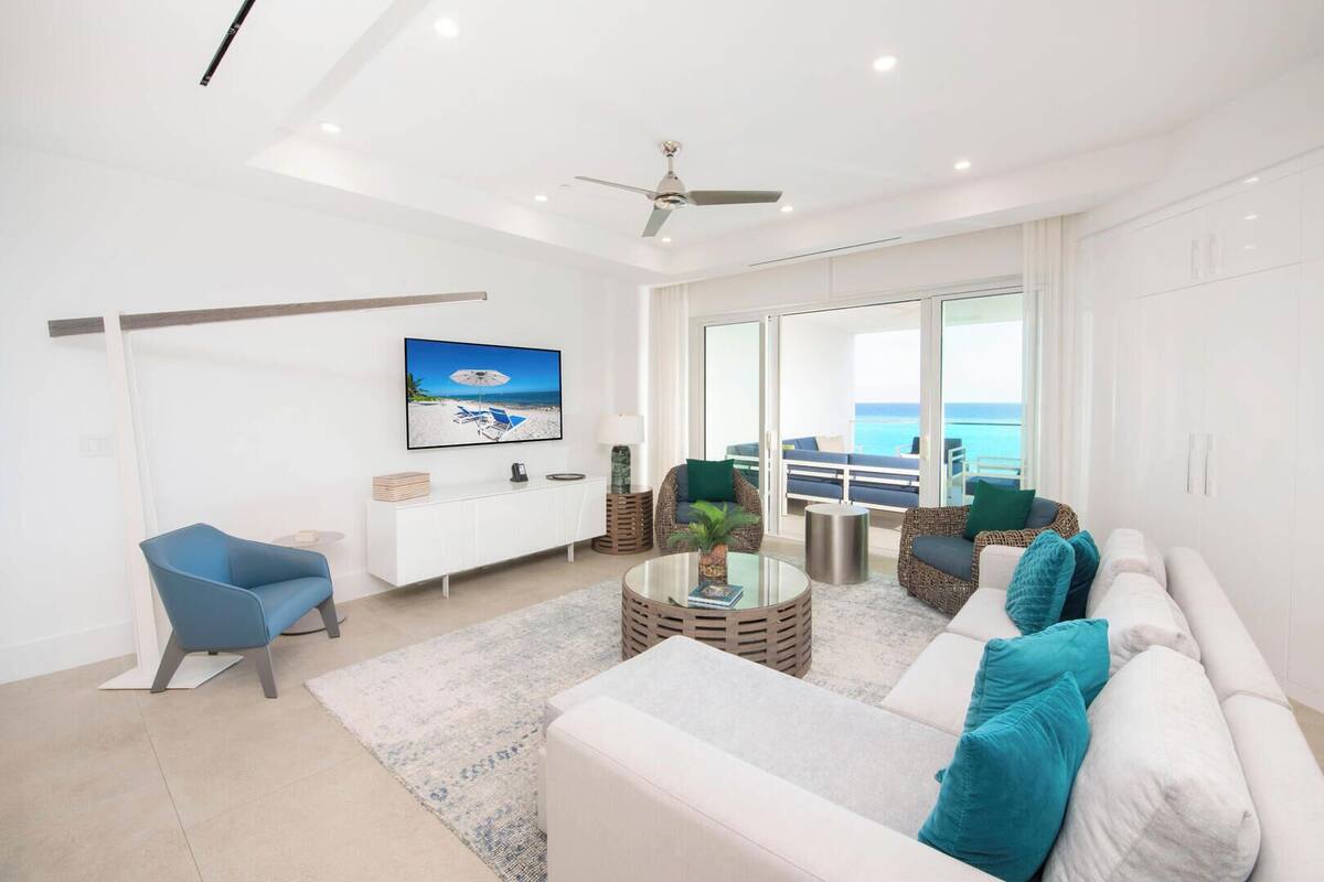 A modern living room with a white sofa, blue armchair, and a television mounted on the wall.