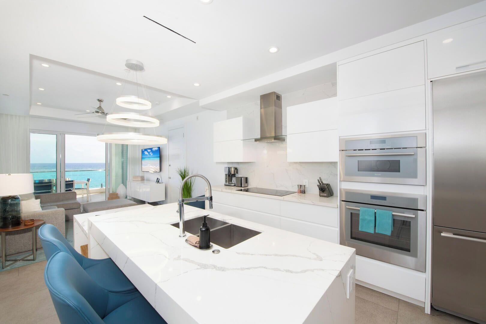 A modern kitchen with a central island, stainless steel appliances, and a view of the ocean.