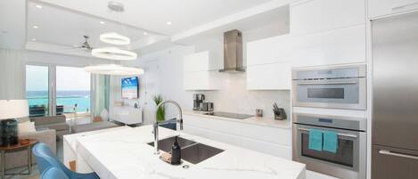 A modern kitchen with a central island, stainless steel appliances, and a view of the ocean.