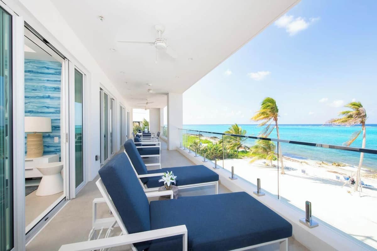 A balcony with lounge chairs, a ceiling fan, and a view of the beach.