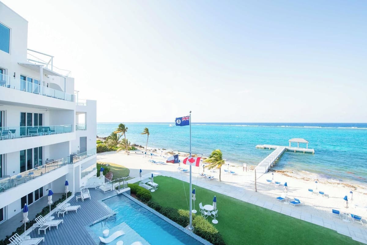 A hotel with a pool, beach, and ocean view.