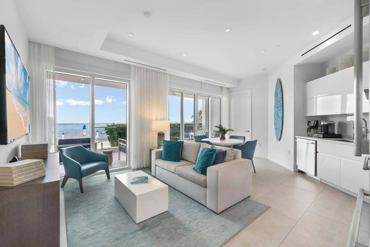 A modern living room with a sofa, armchairs, a coffee table, and a view of the ocean.