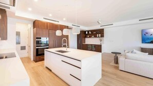 Une cuisine moderne dotée d’un îlot central, de meubles en bois et de luminaires suspendus.