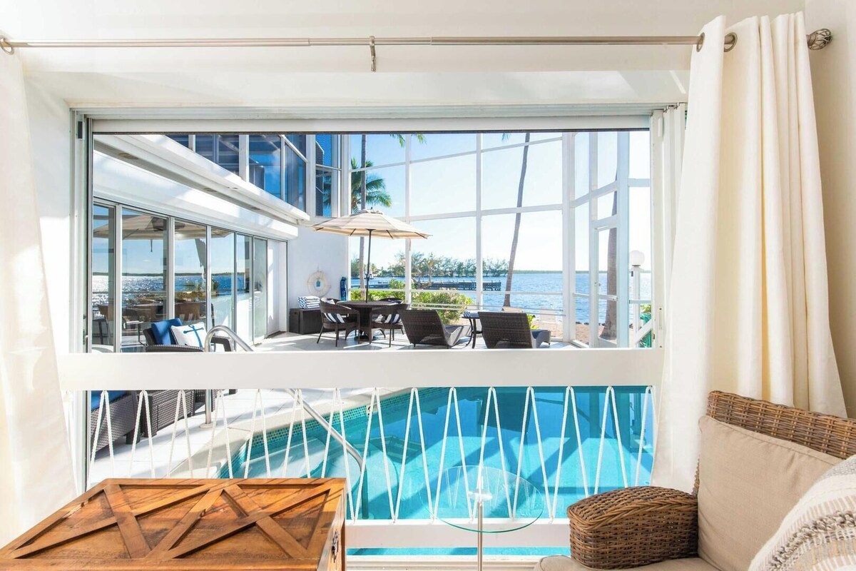 A modern room with a large window overlooking a pool and the sea.