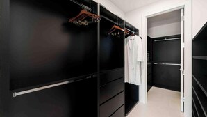 Ein begehbarer Kleiderschrank mit schwarzen und weißen Stauraumelementen, einem Holzkleiderständer und einem weißen Bademantel an einer Stange.