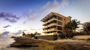 Un hôtel à plusieurs étages doté de balcons, situé sur une côte rocheuse et offrant une vue sur la mer.