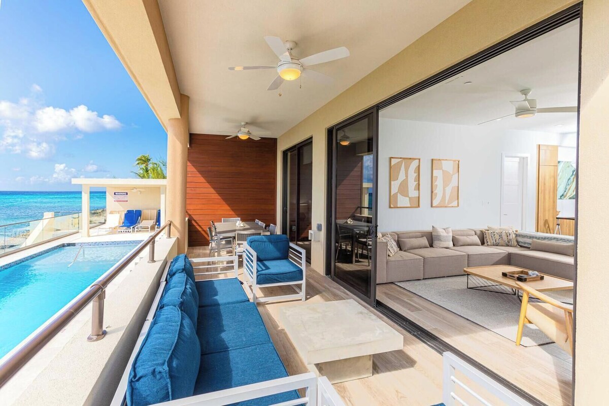 Ein Balkon mit Pool, Sitzgelegenheiten und Meerblick.