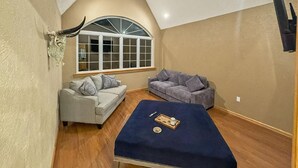 Ein Zimmer mit schrägen Wänden, zwei Sofas, einem kleinen Tischchen mit Tablett und einem Fenster mit dekorativem Bogen.