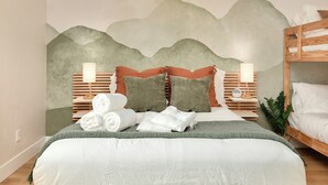 A neatly made bed with pillows and a blanket, a bedside table with a lamp, and a wall mural. - Modern Japandi Home with Fire-Pit Evenings and Fast Internet (Meridian)