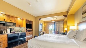 A hotel room with a large bed, wooden cabinets, a microwave, and a small kitchenette. - Wyndham 1-Bedroom Studio in a Premier Resort with Full Amenities (Phoenix)