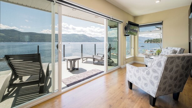 A spacious living area with a large sliding glass door leading to a balcony overlooking a lake. - Private Dock, Kayaks, SUPs, Lakefront Views (Celista)
