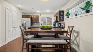 Une cuisine moderne avec des meubles en bois, un îlot central et un coin repas comprenant une table et des chaises en bois.