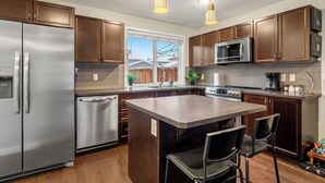 Une cuisine moderne dotée d’appareils électroménagers en acier inoxydable, de meubles en bois et d’un îlot central avec des chaises.
