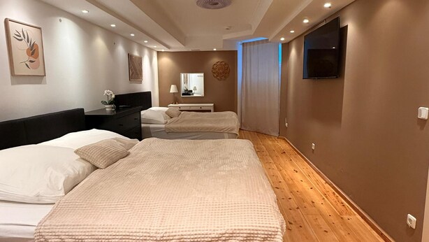 Een hotelkamer met een groot bed, een nachtkastje, een spiegel en een aan de muur bevestigde televisie.