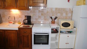 Een compacte keuken met houten kastjes, een wit fornuis, een magnetron en een spoelbak.