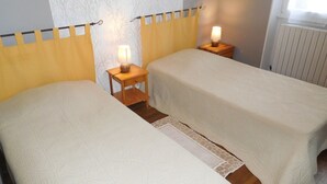 Een kamer met twee bedden, elk voorzien van een nachtkastje en een lamp.
