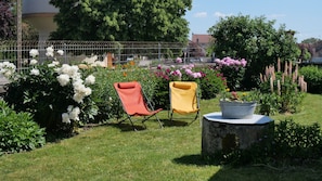 Un jardin avec deux chaises, une plante en pot et une variété de fleurs.