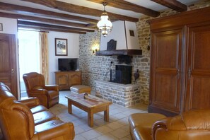 A cozy living room with leather sofas, a wooden coffee table, a stone fireplace, and a television.