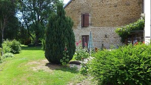 A stone building with a garden in front, including a large tree and a small umbrella. - The Récourt Gardens (Récourt)