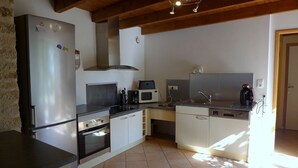 A compact kitchen with a refrigerator, oven, microwave, and sink. - The Récourt Gardens (Récourt)