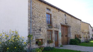 A stone building with a wooden door, windows, and flower boxes. - The Récourt Gardens (Récourt)