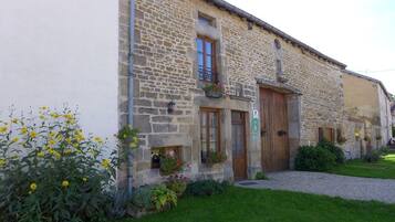 Un bâtiment en pierre avec une porte en bois, des fenêtres et des jardinières.