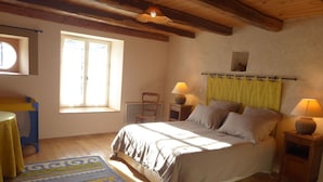 Une chambre à coucher avec un lit, deux lampes de chevet, une chaise, une petite table et une fenêtre.