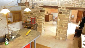 Une cuisine rustique avec des murs en pierre, un comptoir en bois et un luminaire suspendu.