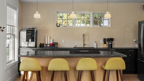 A modern kitchen with a central island, pendant lights, and a window with a view. - Assemble Boise (Boise)